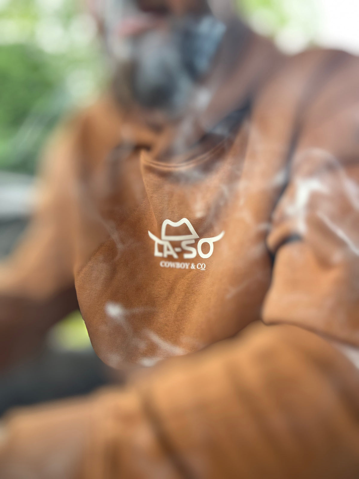 Hoodie Le Rancher couleur caramel, de face avec le logo de La-So au centre de la poitrine, entourer de fumée pour un effet embrouillé.